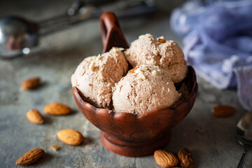 Sweet dessert: Almond ice cream with nuts in a brown creamer. Balls of chocolate ice cream on a...