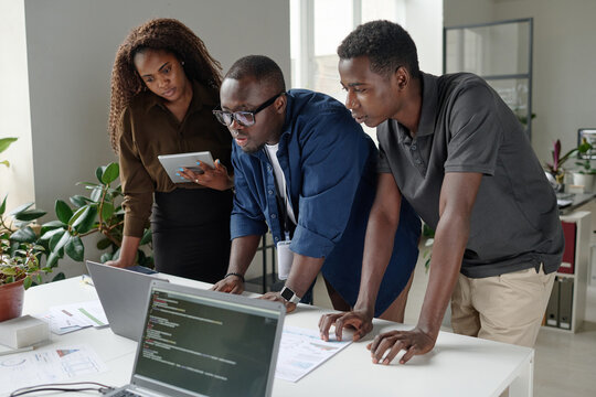 African American coworkers looking at codes together, they focused on working process