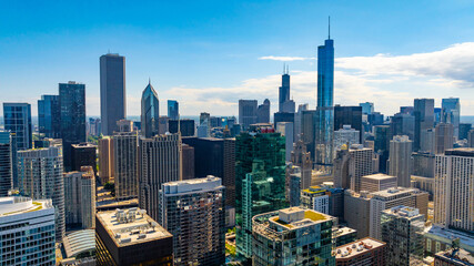 Fototapeta premium Flying up to high-rise buildings in the downtown of Chicago, Illinois, United States. Facades of the buildings are lit with bright summer sun.