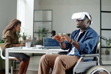 African American worker with disability gesticulating while playing VR game during break, his...