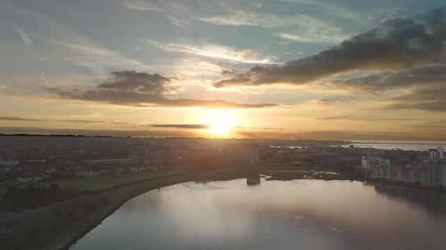 Poole Sun rising over poole harbor with reflections of the clouds in the water