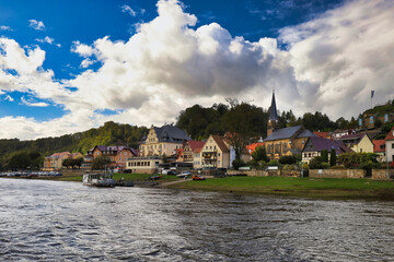 Fototapeta premium Blick von der Elbe auf die Uferpromenade vom Kurort Wehlen mit der Radfahrerkirche und historischen Fachwerkhäusern am 29. September 2024, Sächsische Schweiz, Sachsen, Deutschland