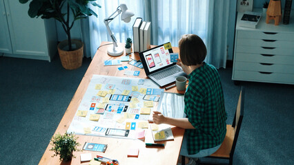 Top view of manager design UX, UI system while sitting at table and looking at tablet with program...