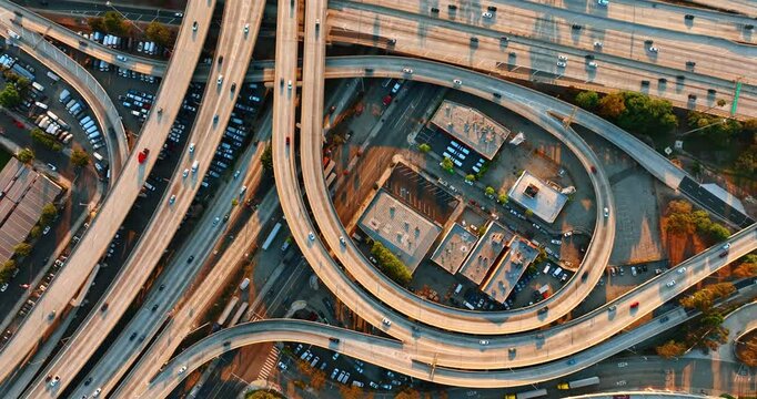 Highways, loops and freeways of Los Angeles interchange are full of moving cars. Top view on the transport in a metropolis, both riding and standing at parking lots.
