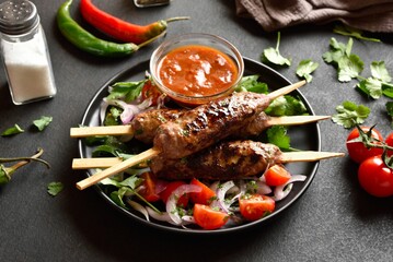 Grilled lula kebab on skewers served with fresh vegetables and sauce