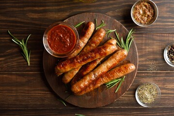 Grilled juicy sausages on platter on wooden background