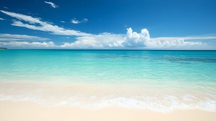 Obraz premium Quiet beach with soft white sand and gentle turquoise waves under a bright blue sky, perfect for a tranquil and relaxing beach day.