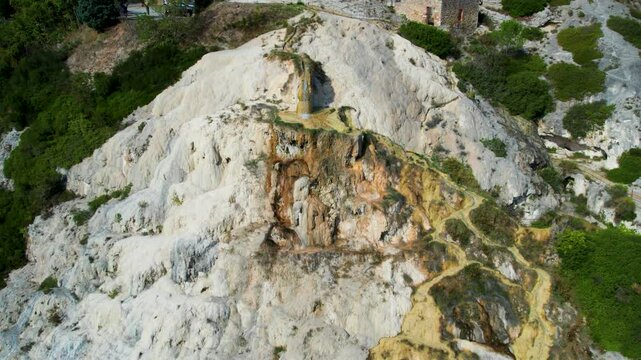 Bagno Vignoni&rsquo;s natural beauty captured with a winding path through rocky terrain and greenery, offering a peaceful escape into nature under a bright blue sky