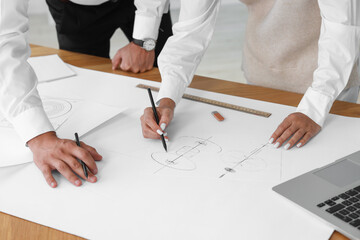 Architects making engineering drawing at wooden table in office, closeup