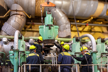The engine crew carefully transports a dismantled exhaust valve from the main engine, preparing it...