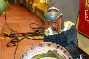 A crew member from the engine department uses a pneumatic brush to clean a section of the exhaust...