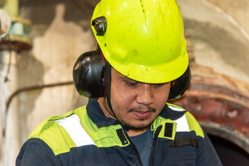 A close-up of the upper body and head of a marine engineer officer, focused on performing duties in the engine room during the repair of the ship’s main engine.