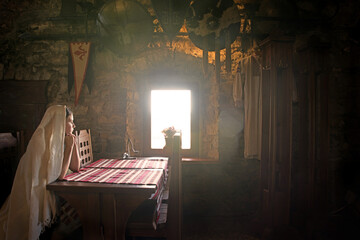 A girl sits at a table by the window in an ancient castle