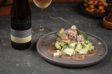 Portion of salad with iceberg leaves and beef tongue with wine