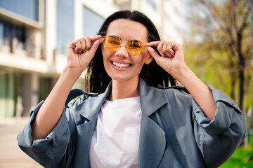 Photo of shiny attractive lady dressed grey coat dark eyewear enjoying good weather outdoors town...