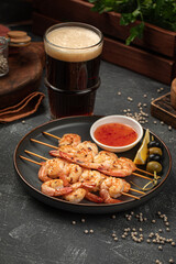 Portion of shrimp skewers with sweet and sour sauce with beer