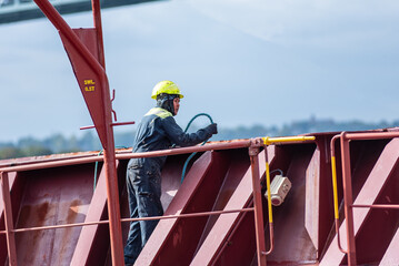 A deck crew member prepares the forward mooring station for docking, focused on securing the ship...