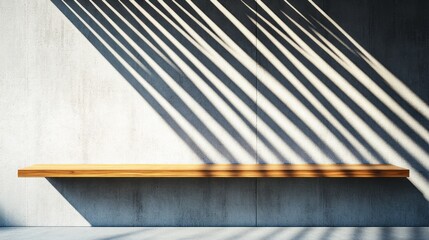 Obraz premium A wooden shelf rests against a plain concrete wall, where long shadows create striking patterns in the late afternoon sunlight, enhancing the minimalist aesthetic of the room