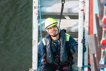 A deckhand prepares the pilot ladder as the ship readies for port entry. Secured in a safety...