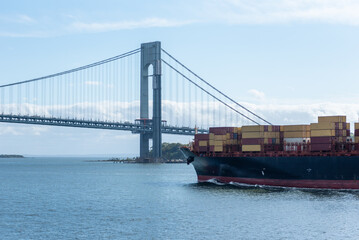 Large, fully loaded container ship sailing under the Verrazano-Narrows bridge on her way out of New...