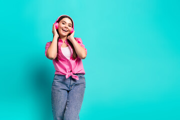Photo portrait of lovely teen lady headphones listen music have fun dressed stylish pink garment isolated on cyan color background