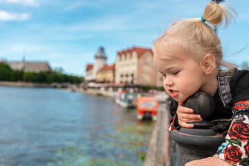 A little child toddler girl in a denim jumpsuit travels to the Fishing village in Kaliningrad, an...