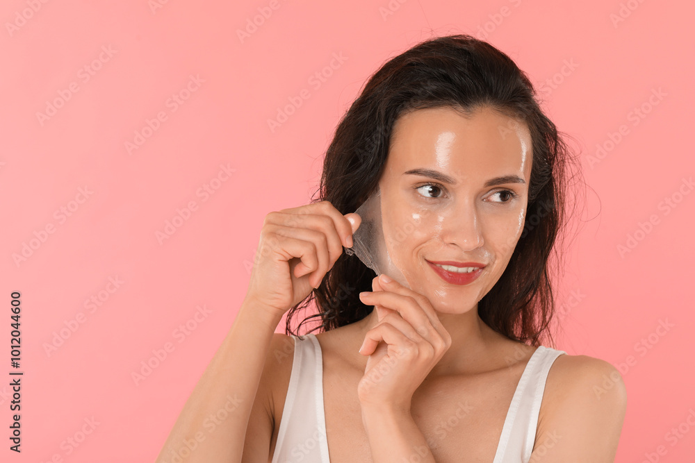 Poster Smiling woman peeling off face mask on pink background. Space for text