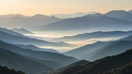Fototapeta premium Misty mountains with layered peaks and valleys at sunrise.