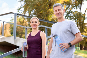 Obraz premium Happy couple with bottles of water in park