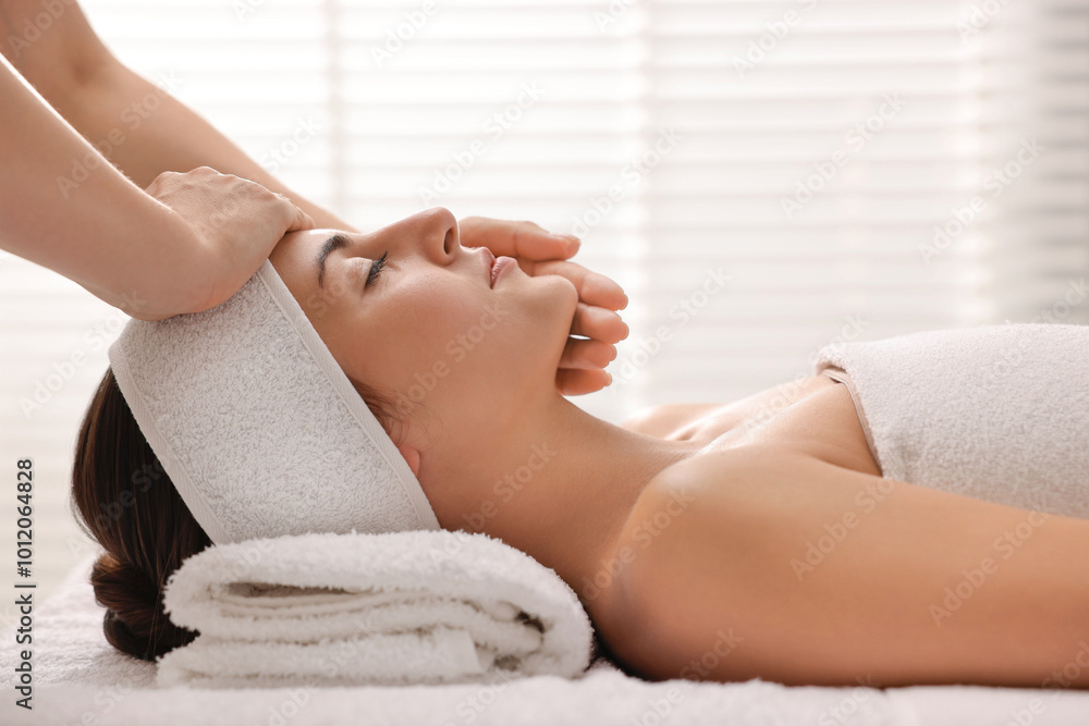 Wall mural Attractive woman enjoying face massage in spa salon