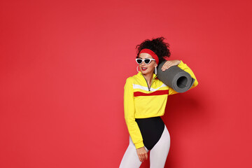 Obraz premium Aerobics. Woman in sportswear holding fitness mat on red background, space for text
