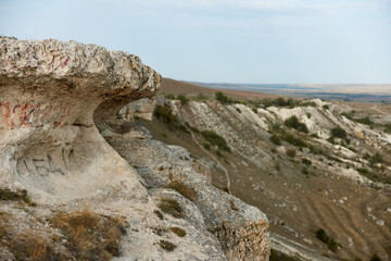 Majestic rock formations with graffiti and person standing on cliff edge in beautiful landscape