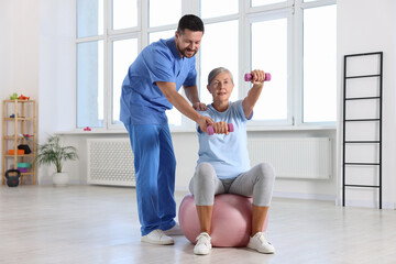 Fototapeta premium Senior patient exercising under physiotherapist supervision in rehabilitation center