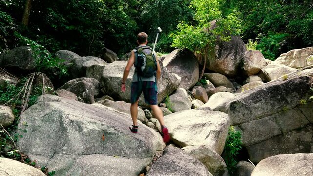 A tourist climbs a pile of giant rocks in the jungle