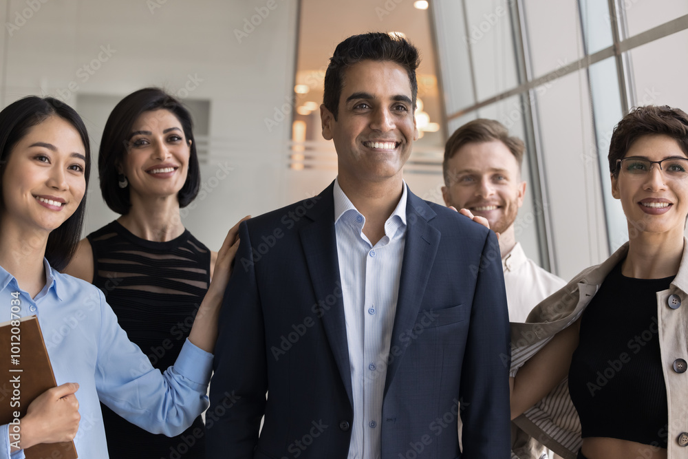 Poster positive successful male indian boss posing for portrait with diverse employees, looking away with t