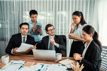 Diverse group of business analyst team analyzing financial data report paper on office table. Chart and graph dashboard by business intelligence analysis for strategic marketing planning Habiliment