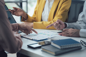 Strategic Collaboration: A close-up shot of a diverse team of business professionals engaged in a lively discussion, pointing at a document and laptop screen.  A sense of teamwork, analysis.