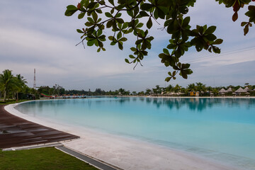 Tropical resort scene in luxury Treasure Bay hotel on Bintan Island, Indonesia. Exotic palm trees in front of large clear blue swimming pool. Tranquility and relaxation. Getaway to recharge. Vacation
