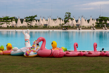 Tropical resort scene in luxury Treasure Bay hotel on Bintan Island, Indonesia. Collection of colorful inflatable toys (flamingos, ducks, llama) in front of large clear blue swimming pool. Vacation