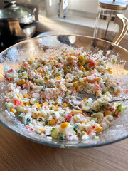 Imitation crab salad with crab sticks, corn, eggs, cucumber and rice in bowl. Top view close up