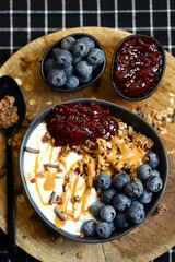 bowl with chocolate granola white yogurt peanut butter and raspberry jam
