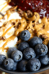 bowl with chocolate granola white yogurt peanut butter and raspberry jam