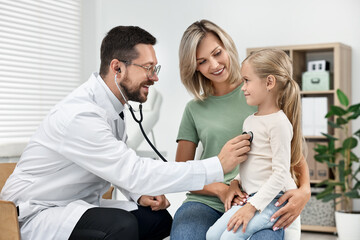 Obraz premium Doctor examining little girl with stethoscope and her mother in hospital