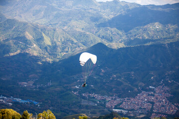 People paragliding over the beautiful mountains of the Antioquia department in Colombia. Tandem Paragliding. Extreme sport concept.