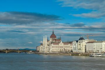 Naklejka premium Iconic Hungarian Parliament Building along the Danube riverbanks in Budapest, Hungary. Ornate facade with carvings and statues. Architectural heritage. Towering spires and Gothic arches with majesty
