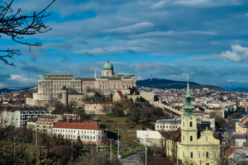 Fototapeta premium Panoramic view of iconic Buda castle in Budapest, Hungary. Sprawling complex of buildings, dominates the center of the scene. The landmark sits atop a hill overlooking the city and the Danube River.