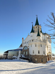Beautiful white princess castle building stands majestically on a snowy landscape under a clear blue sky. Architectural design and winter setting create a fairy tail and fantasy