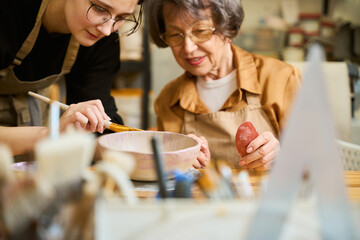 Elderly lady learns to work with clay in ceramics studio