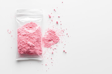 Pink cocaine - Pink powder in a plastic bag with scattered particles on a white surface