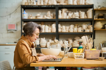Lady is sitting at a table and working on laptop